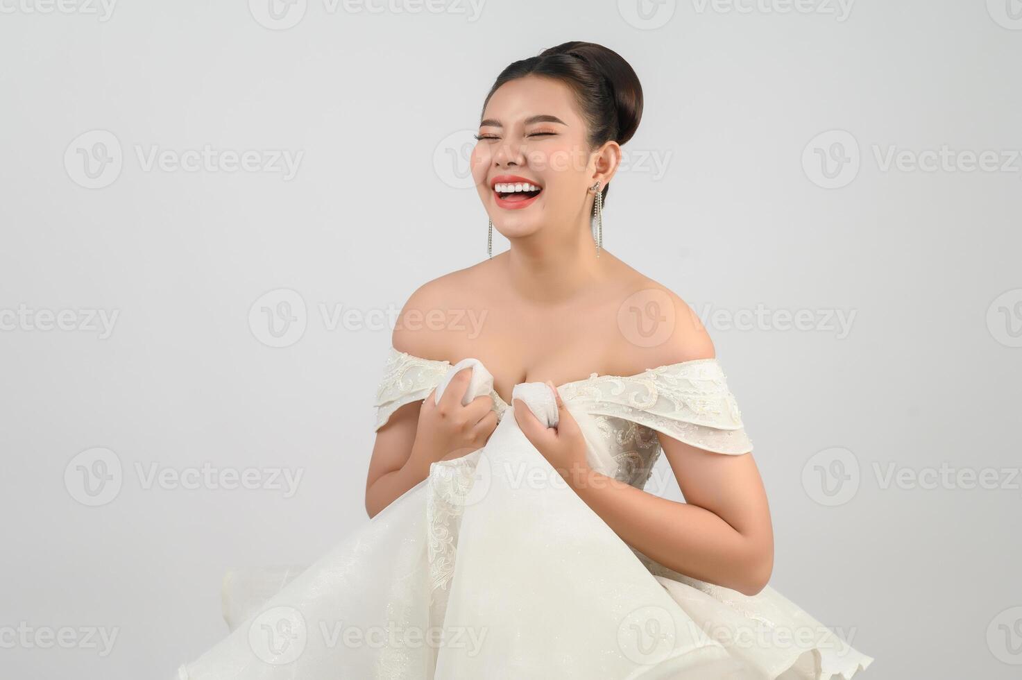 Jeune belle mariée asiatique souriante avec plaisir sur fond blanc photo