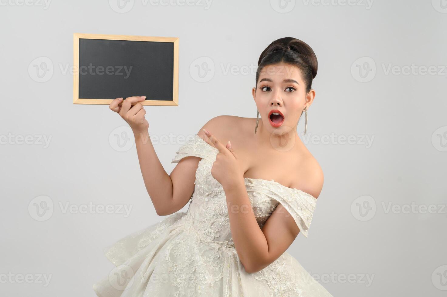 jeune belle mariée asiatique pose avec un tableau blanc à la main photo