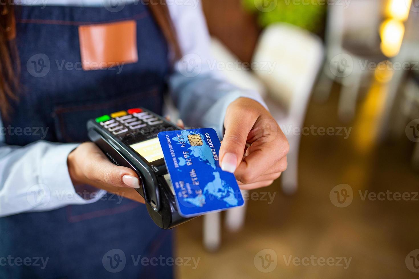 concept de paiement sans contact, femme tenant une carte de crédit près de la technologie nfc sur le comptoir, le client effectue la transaction payer la facture sur la machine de caisse rfid du terminal dans le restaurant, vue en gros plan photo