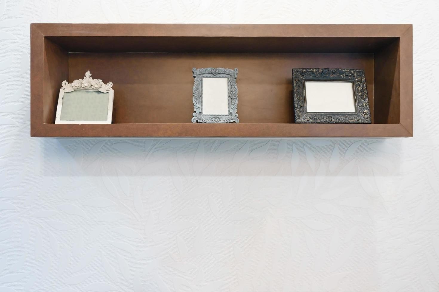Cadre photo vide sur étagère en bois avec fond de mur blanc