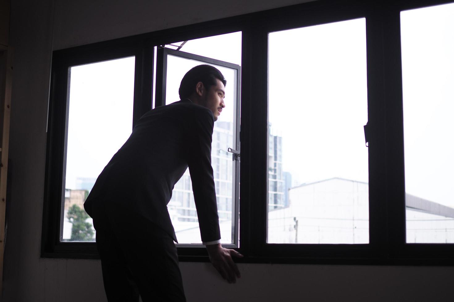 les hommes d'affaires sont stressés, debout à la fenêtre, tristes et déçus. passer du temps seul avec la pression des problèmes photo