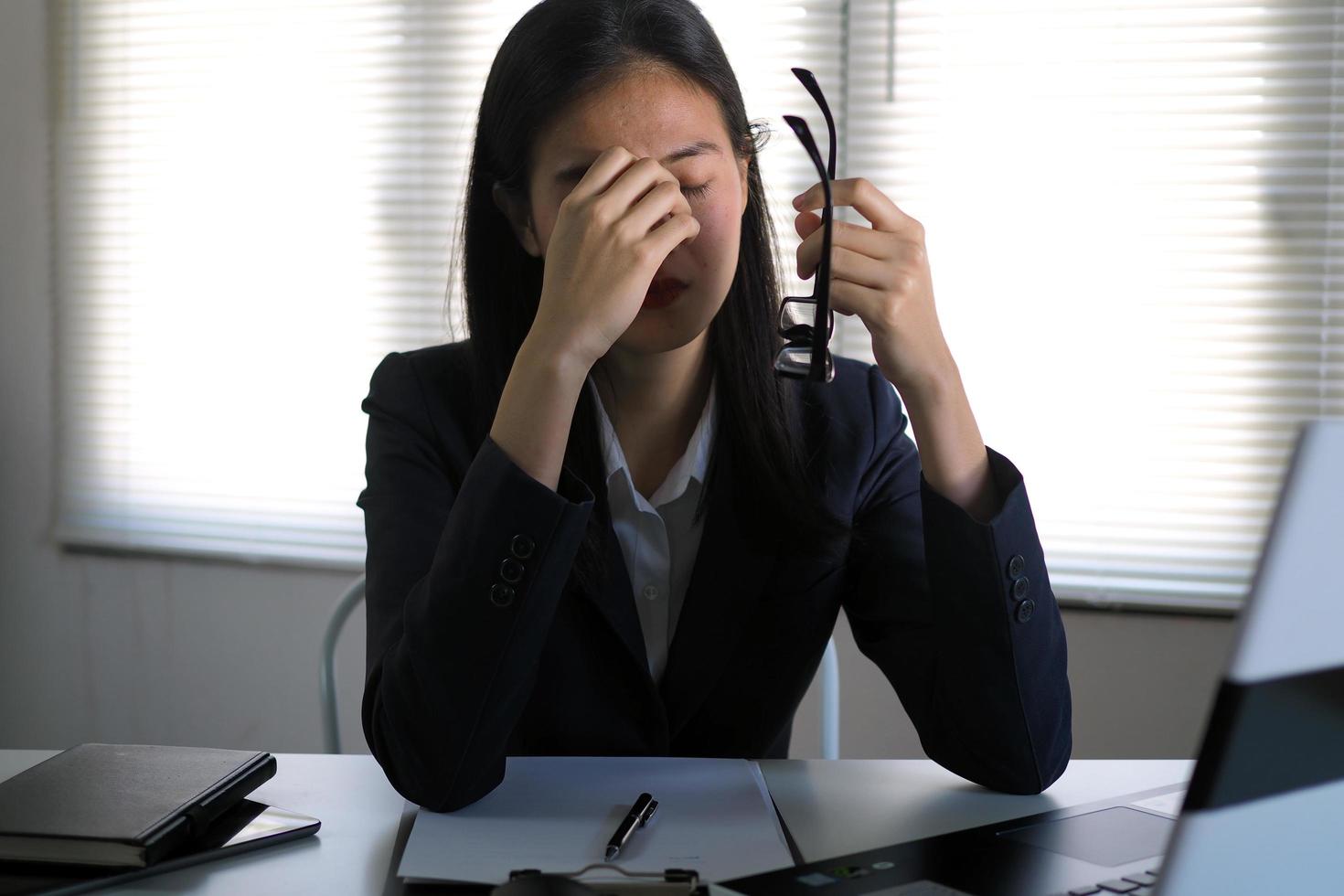 la femme d'affaires a des douleurs oculaires et des maux de tête. de travailler longtemps devant l'ordinateur. concept de syndrome de bureau photo