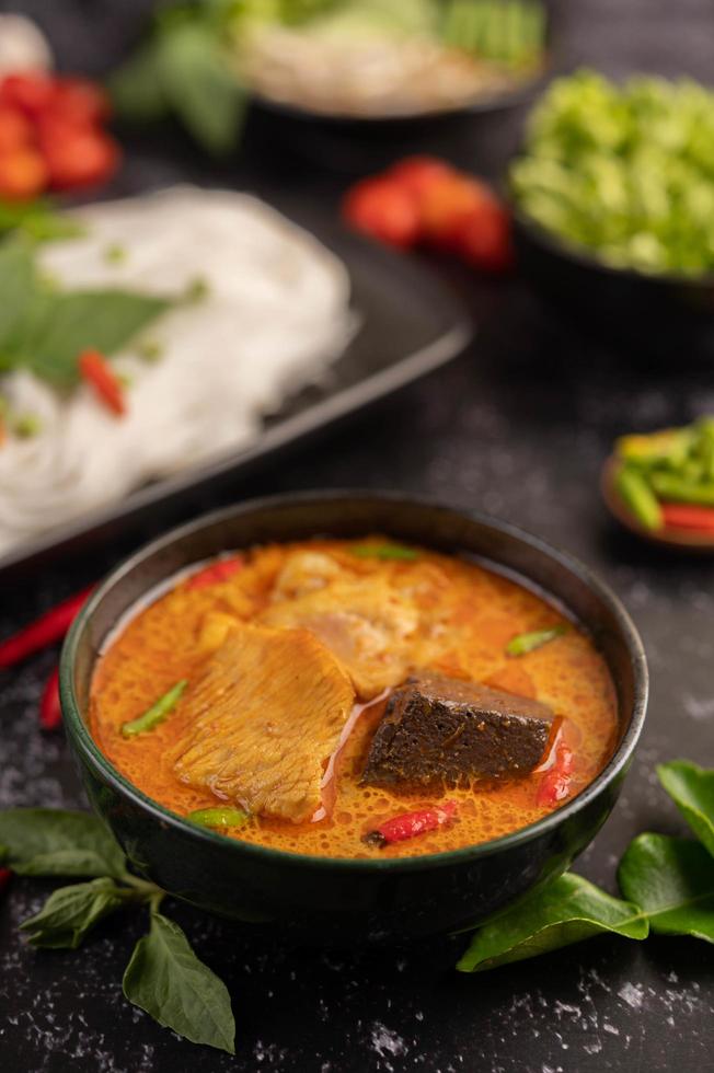 poulet au curry dans une tasse noire avec des nouilles de riz photo