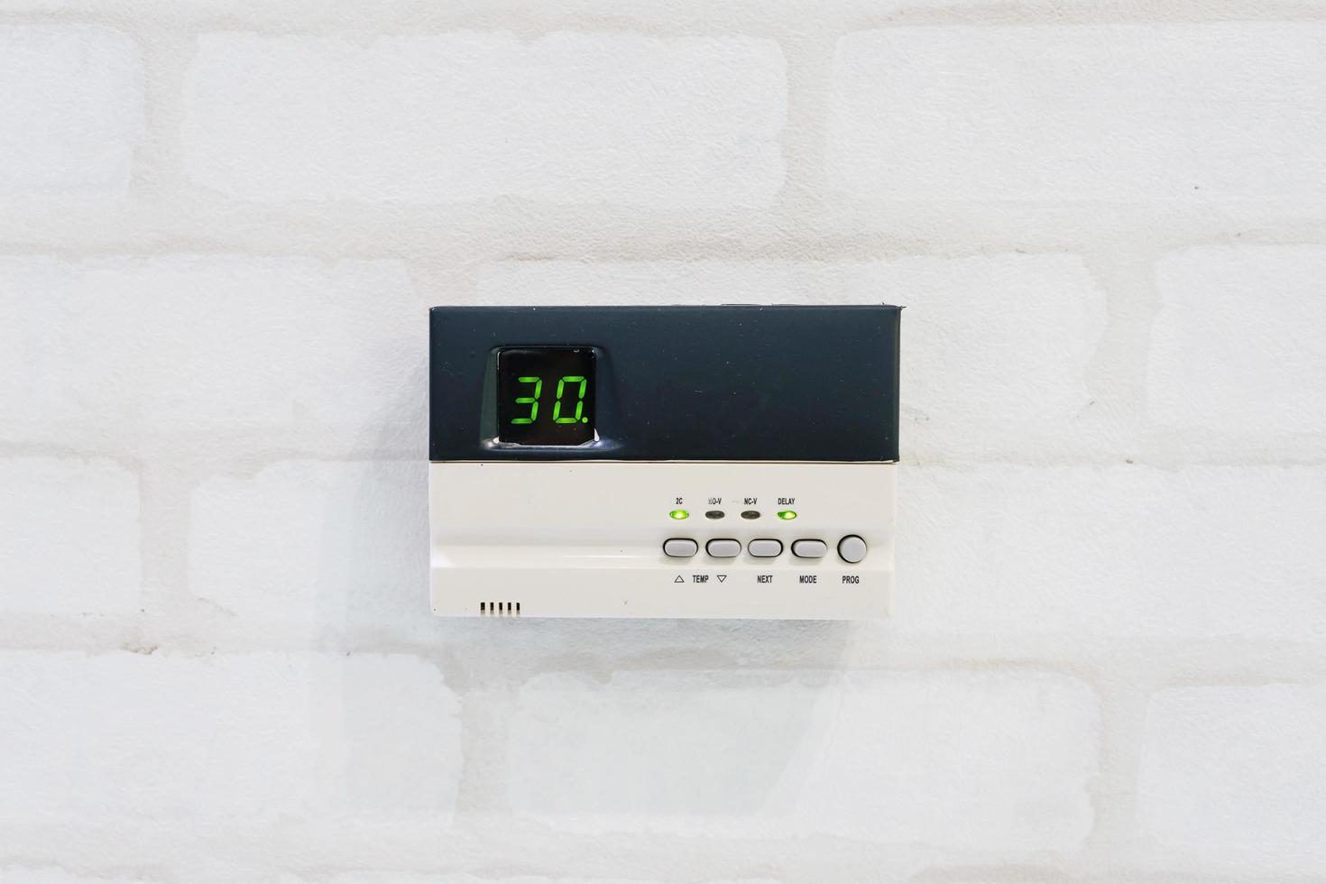 Thermostat de programmation moderne en face de mur de briques blanches avec copyspace et texte photo