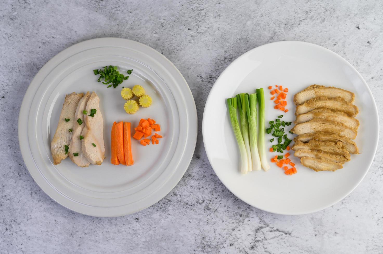 poitrine de poulet cuite à la vapeur sur une assiette blanche avec oignons de printemps et carottes photo