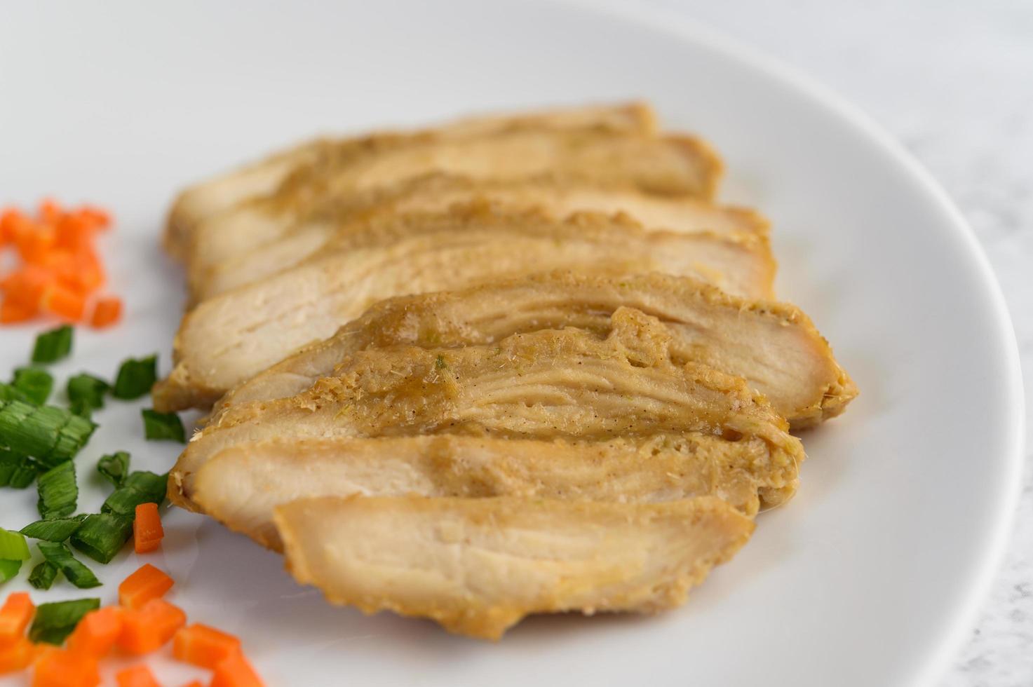 poitrine de poulet cuite à la vapeur sur une assiette blanche avec oignons de printemps et carottes photo