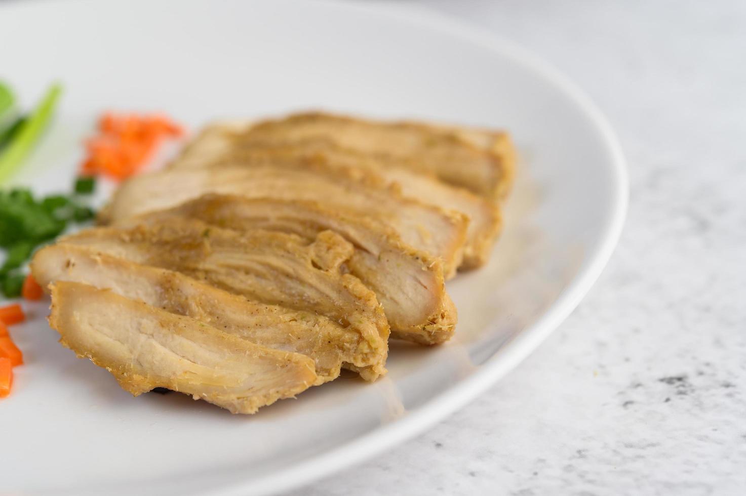 poitrine de poulet cuite à la vapeur sur une assiette blanche avec oignons de printemps et carottes photo