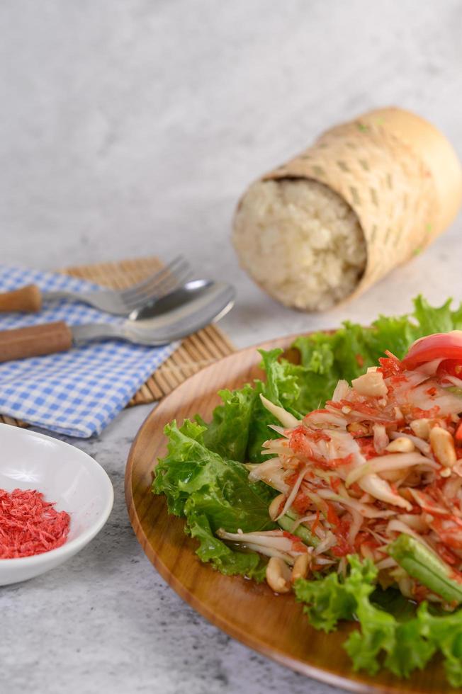 salade de papaye sur une assiette en bois avec riz gluant et crevettes séchées photo