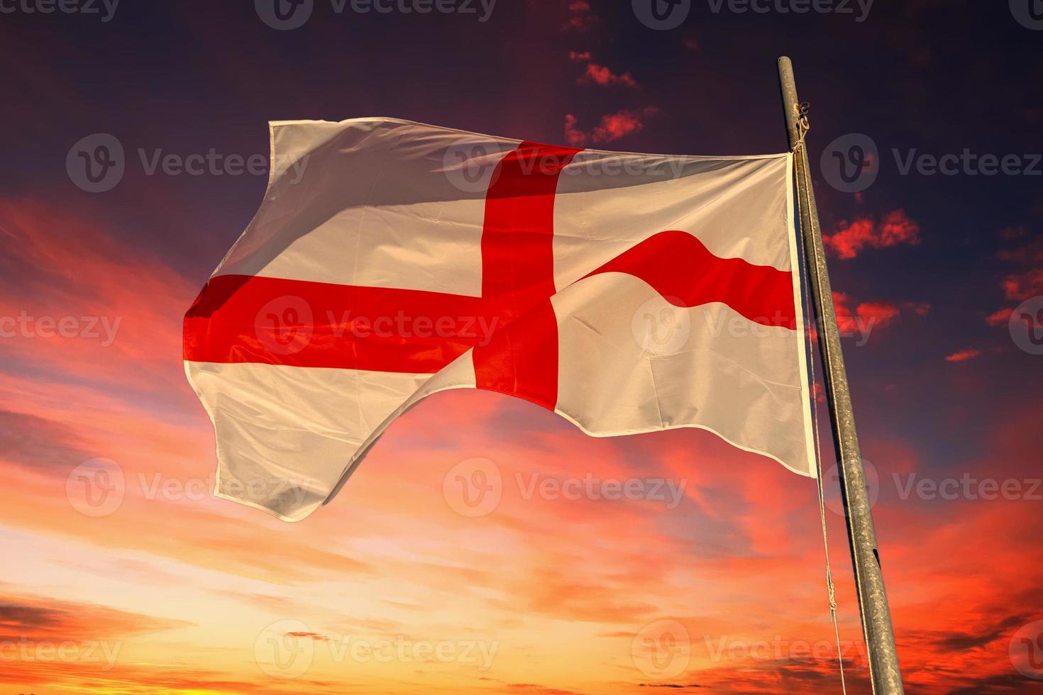 Agitant le drapeau anglais croix rouge sur blanc isolé sur ciel rouge dramatique photo