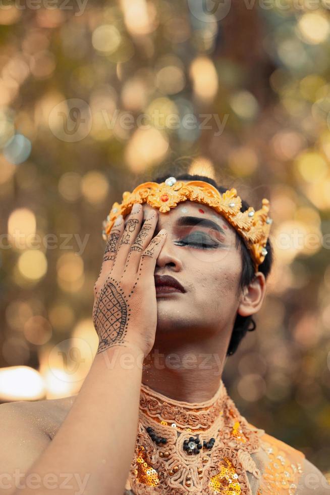 le visage d'un roi tribal portant une couronne d'or et couvrant son visage avec sa main en torse nu photo