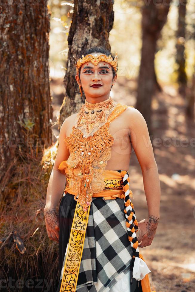 homme balinais debout dans la forêt tout en portant une couronne en or et un collier en or photo