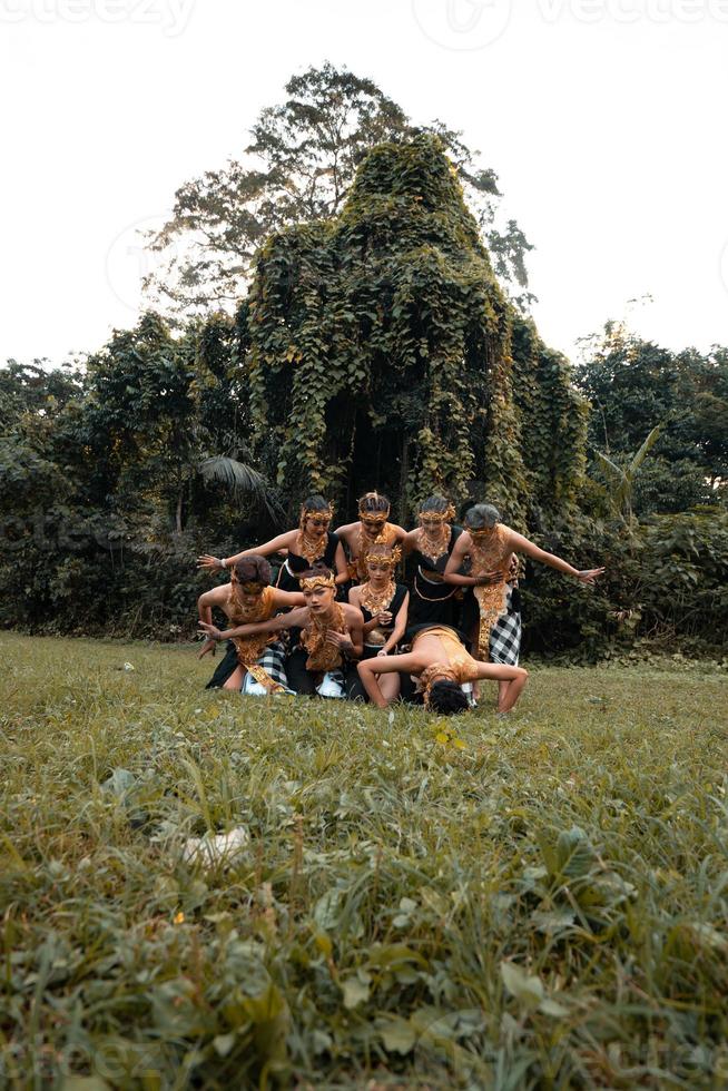 un groupe d'indonésiens dansant pose dans un costume doré tout en se maquillant sur l'herbe verte photo