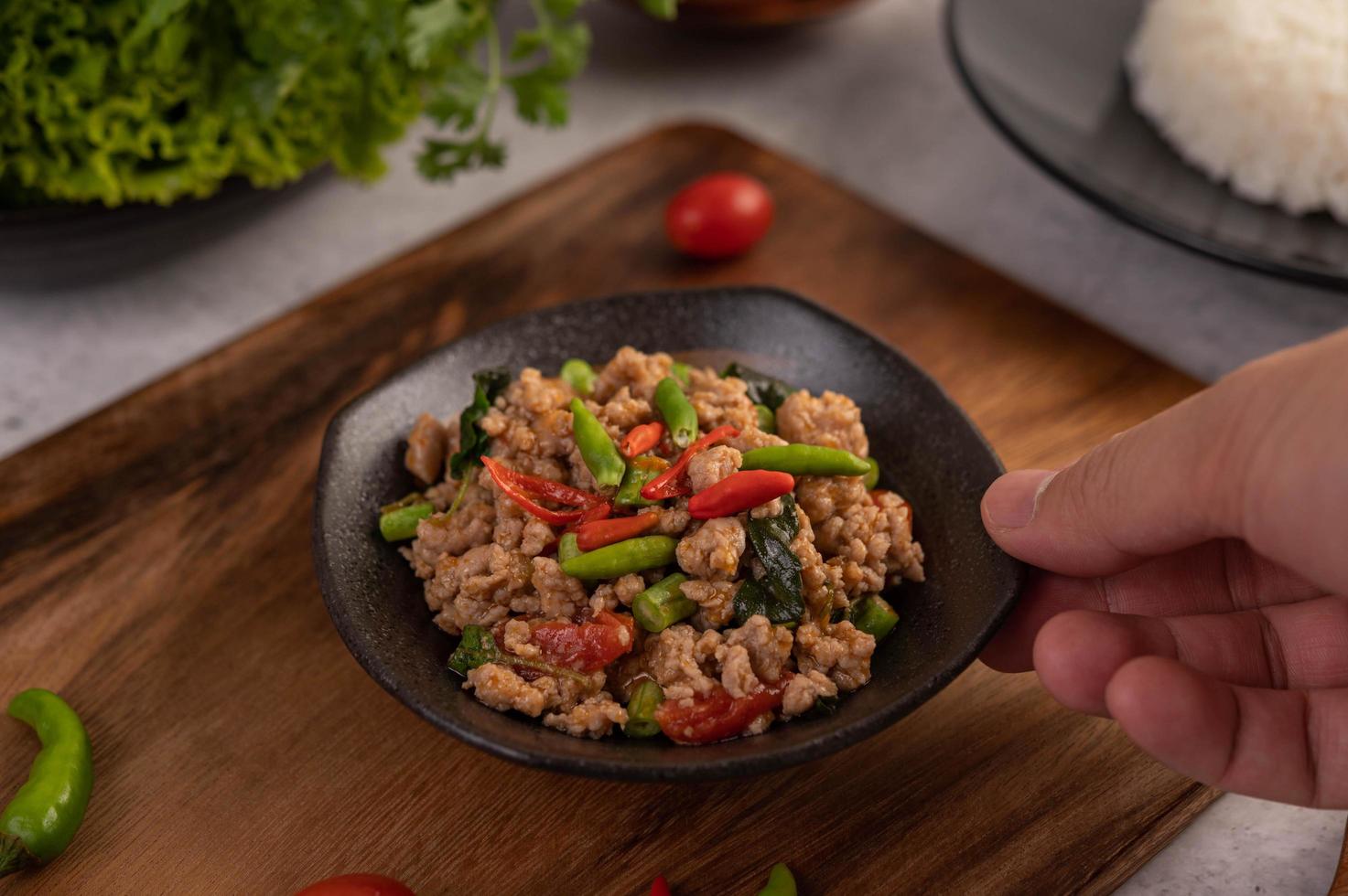 salade de porc hachée épicée avec riz, chili et tomates sur une assiette noire photo