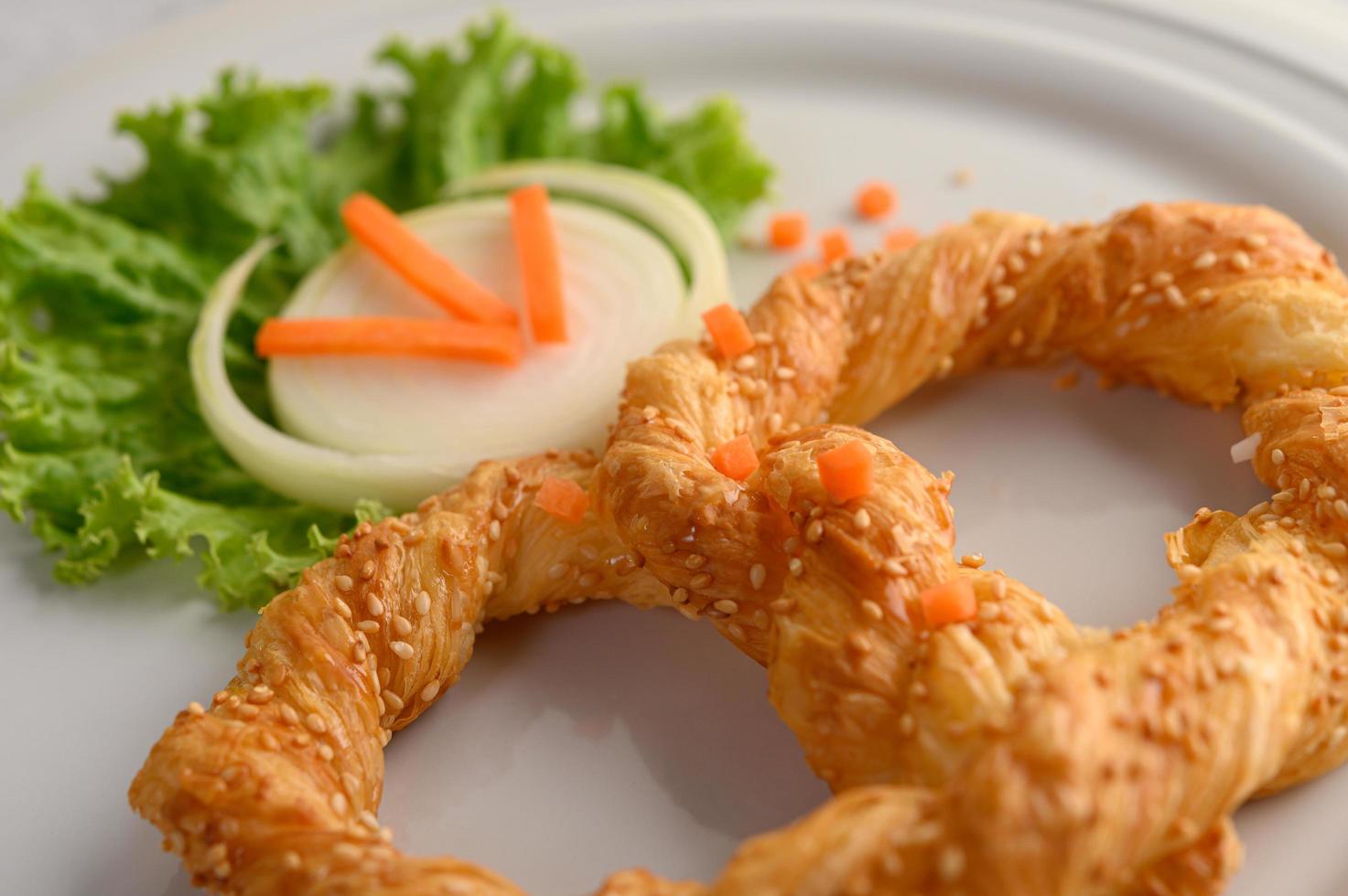 bretzel sur un plat blanc avec laitue et carottes photo