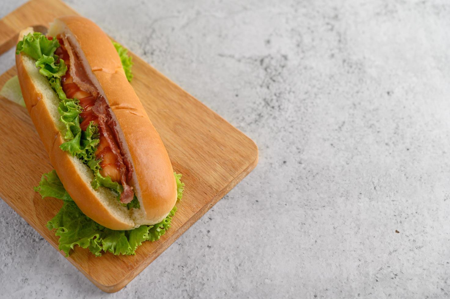 Grand hot-dog avec de la laitue sur une planche à découper en bois photo