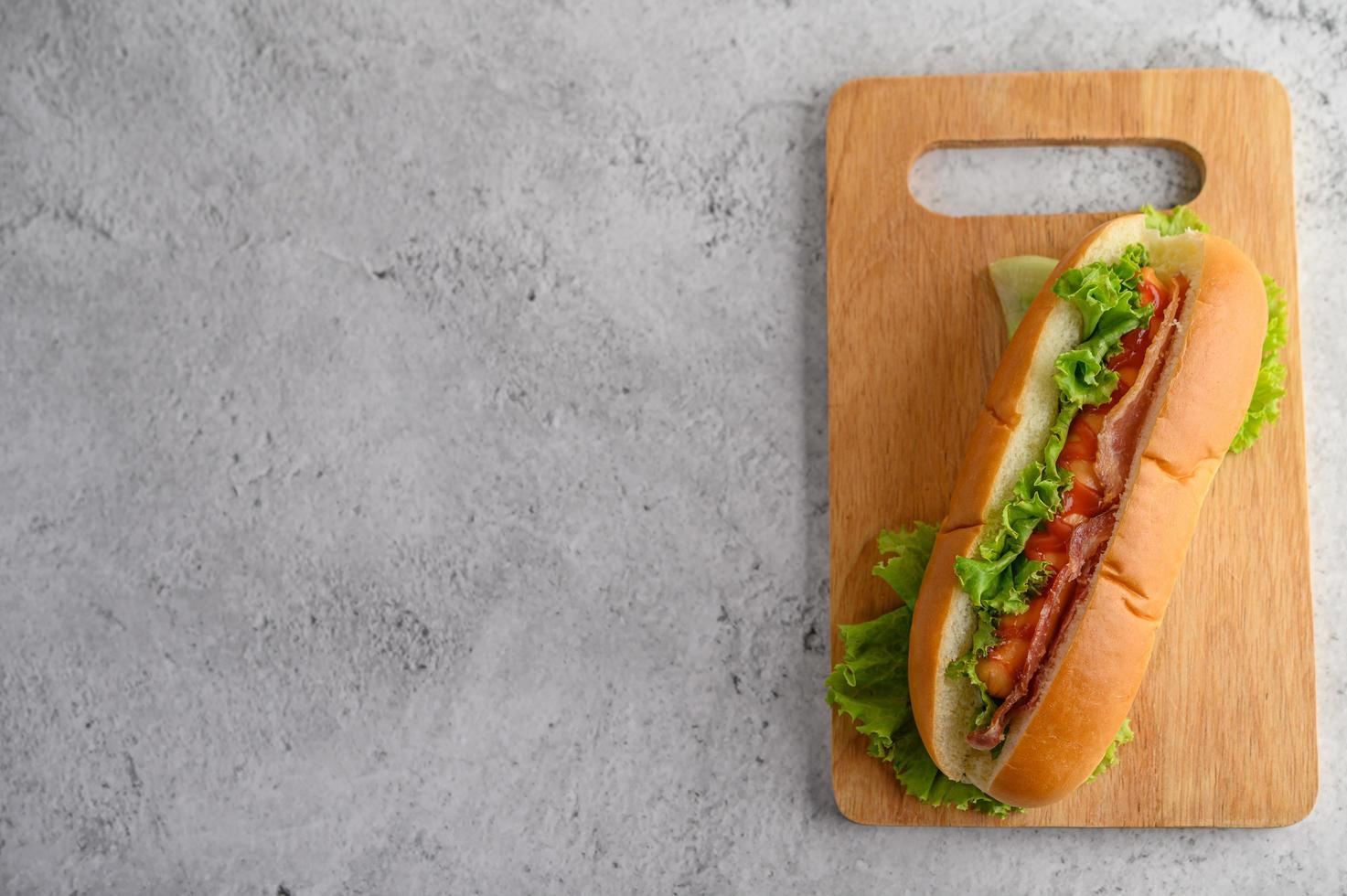 Grand hot-dog avec de la laitue sur une planche à découper en bois photo