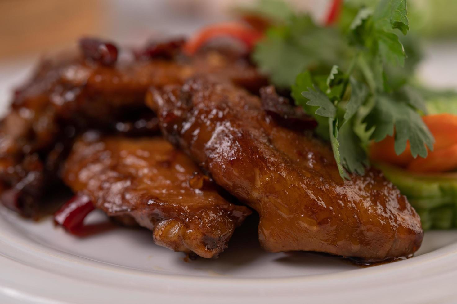 Ailes de poulet frit à la pâte de piment sur un plateau blanc avec du piment et de la coriandre photo