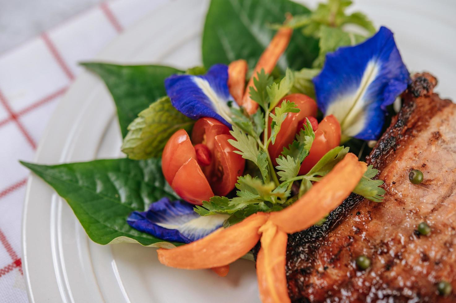 steak de porc à la tomate, carotte, oignon rouge, menthe poivrée, fleur de pois papillon et citron vert photo