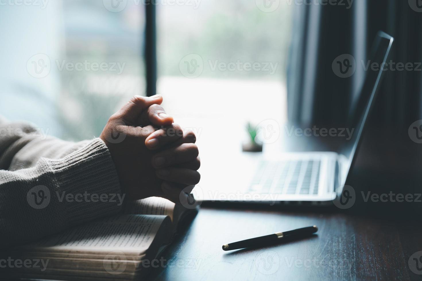 concept de technologie en ligne chrétienne. mains priant de chrétien avec ordinateur portable numérique, église en direct en ligne pour le service du dimanche. une femme catholique asiatique lit le livre de la sainte bible et étudie en ligne. photo