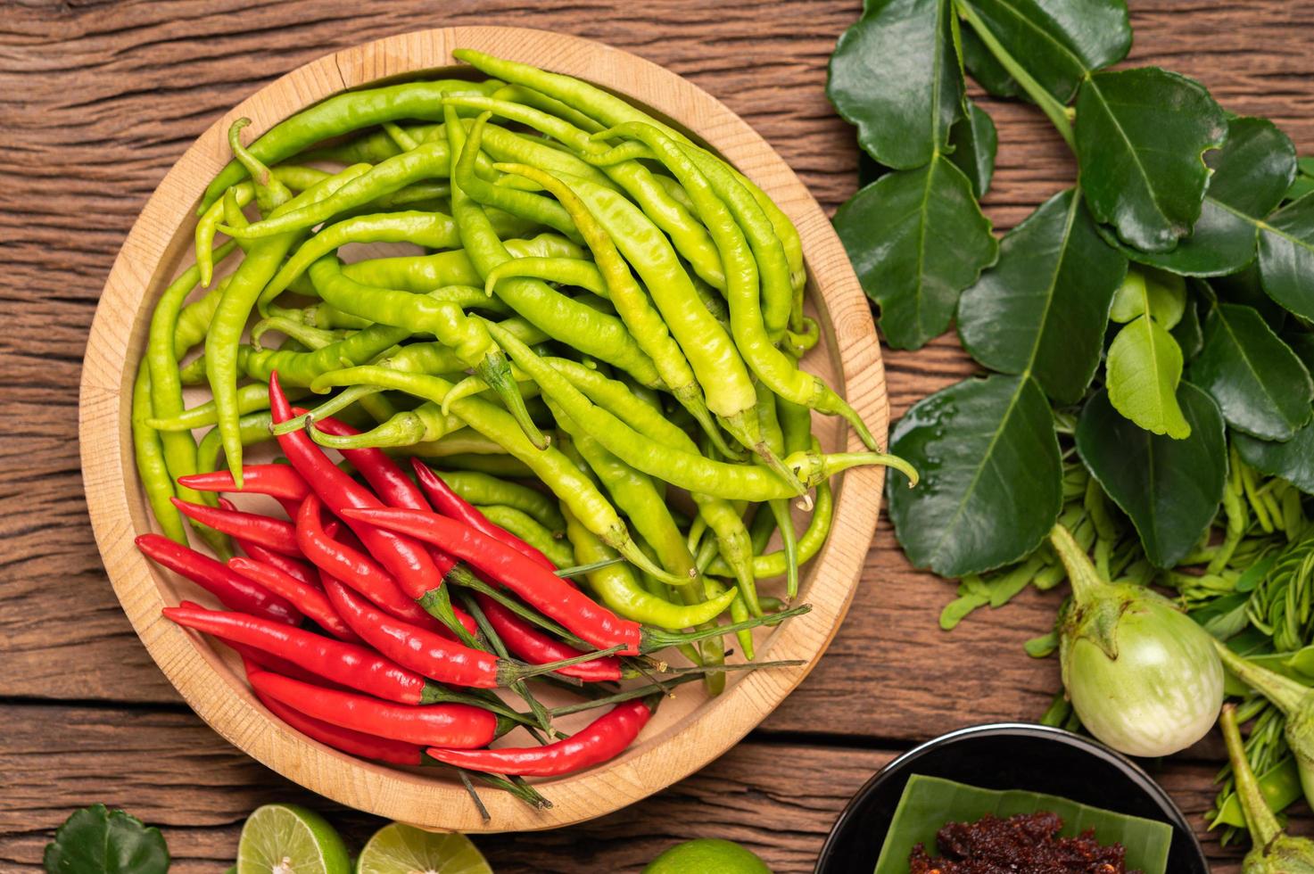 Chili frais sur un plateau en bois avec citron et citron vert kaffir photo