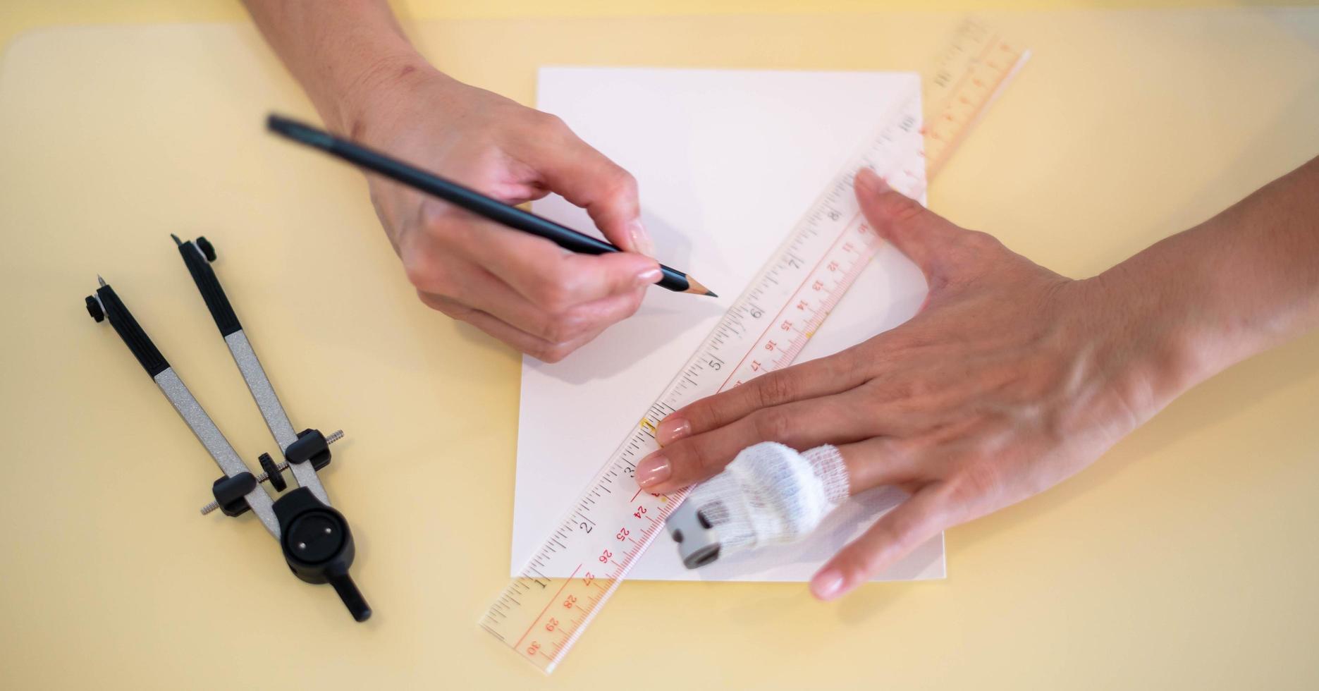 main féminine à l'aide d'une règle avec le crayon se préparant à dessiner et à dessiner sur le papier blanc vide. photo