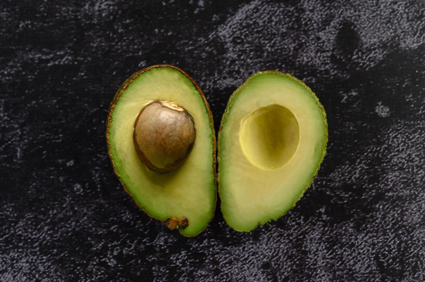 avocat coupé en deux sur ciment noir photo