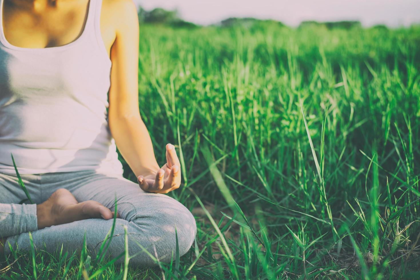 Yoga femme dans la posture du lotus dans un pré ensoleillé photo