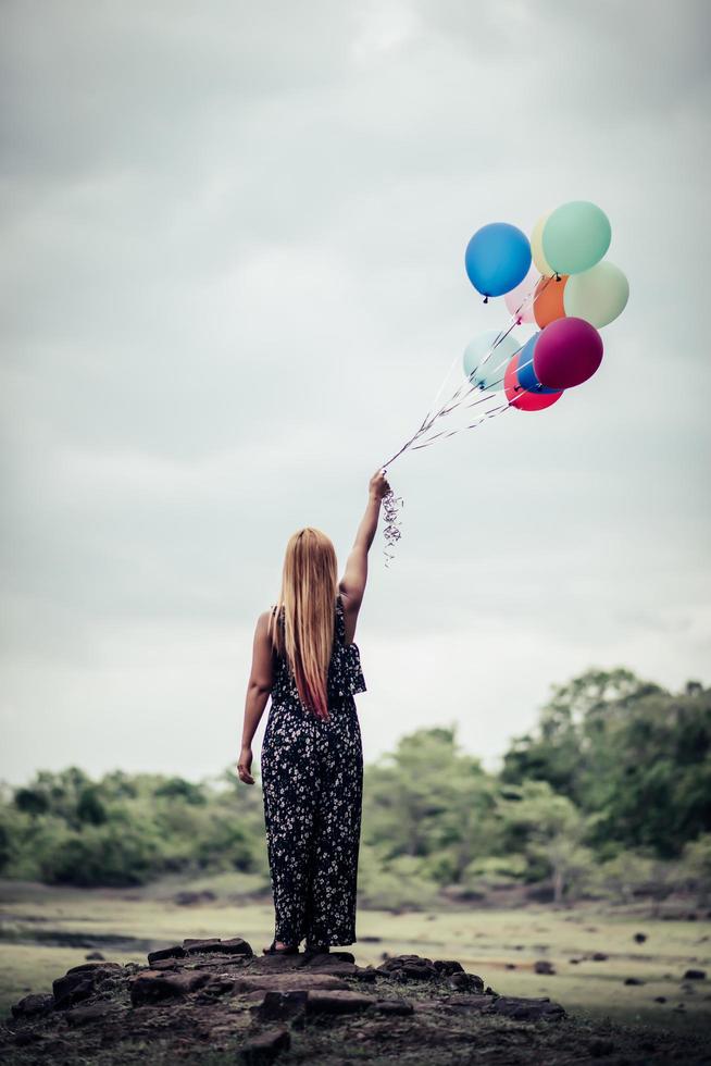 jeune femme tenant des ballons colorés dans la nature photo