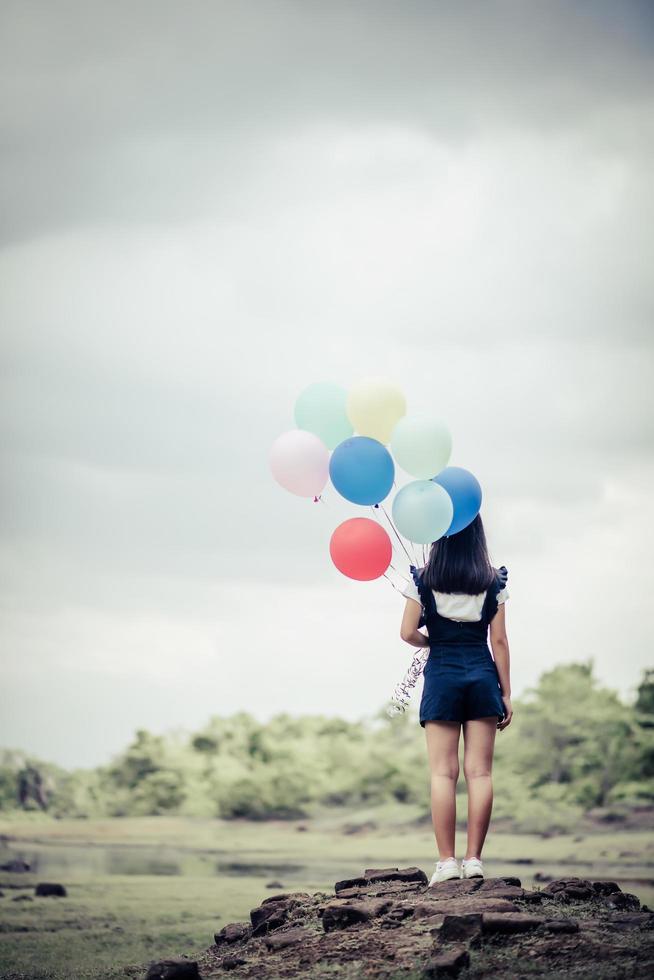 jeune femme tenant des ballons colorés dans la nature photo