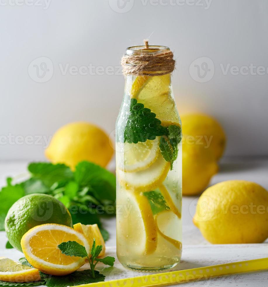 limonade aux citrons, feuilles de menthe, citron vert dans une bouteille en verre photo