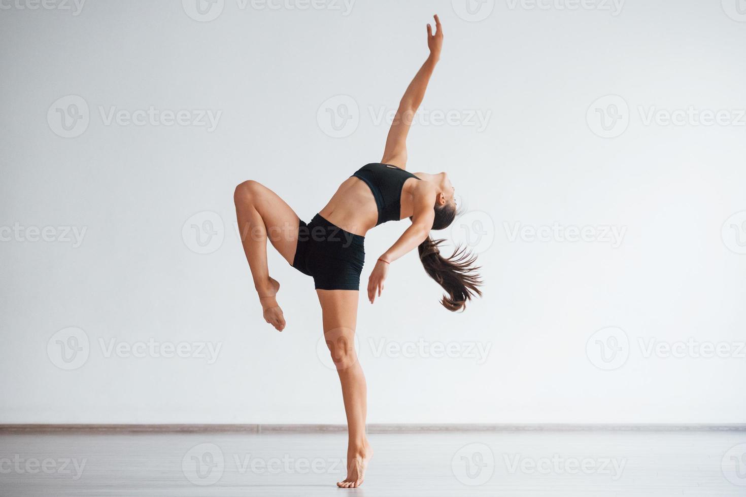 photo pleine longueur. jeune femme sportive en vêtements noirs avec un type de corps mince dans le centre sain faisant des exercices