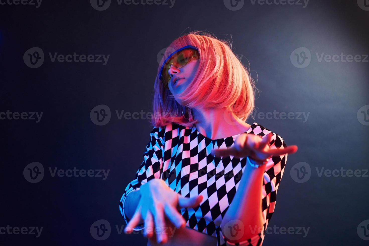 portrait de jeune fille aux cheveux blonds à lunettes en néon rouge et bleu en studio photo
