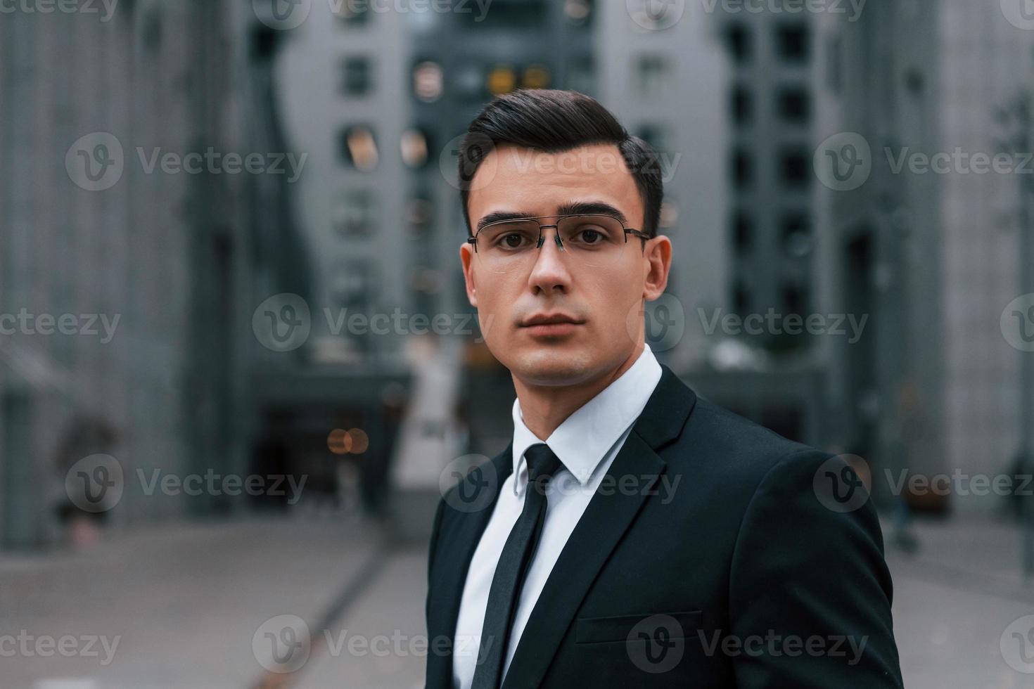 portrait d'homme d'affaires en costume noir et cravate est à l'extérieur de la ville photo