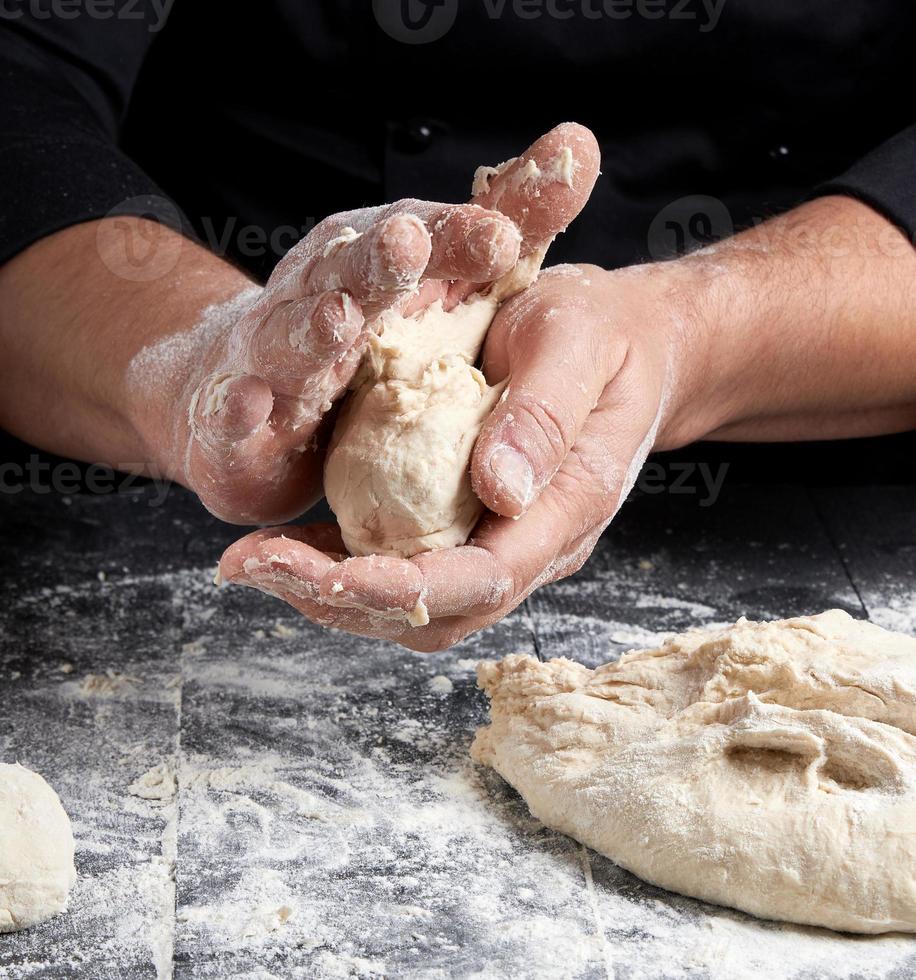 cuisinier faisant des boules de pâte sur une table en bois noire photo