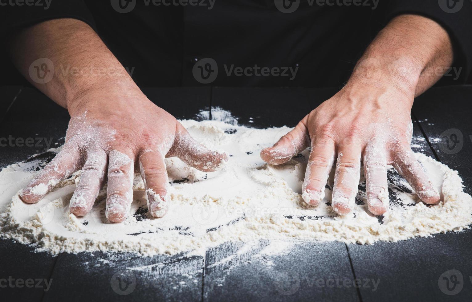 farine de blé blanche sur une table en bois noire et deux mains masculines photo