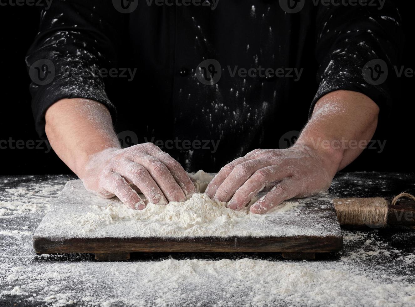 cuisinier en uniforme noir pose les deux mains sur une table photo