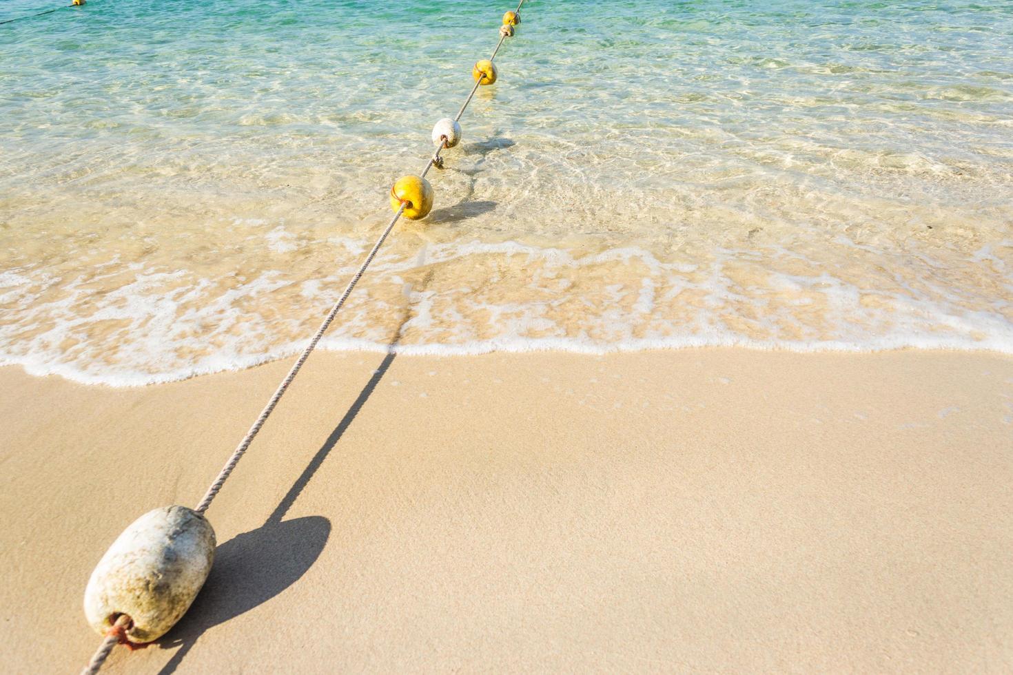 bouées sur corde avec vagues de l'océan sur la plage de sable photo