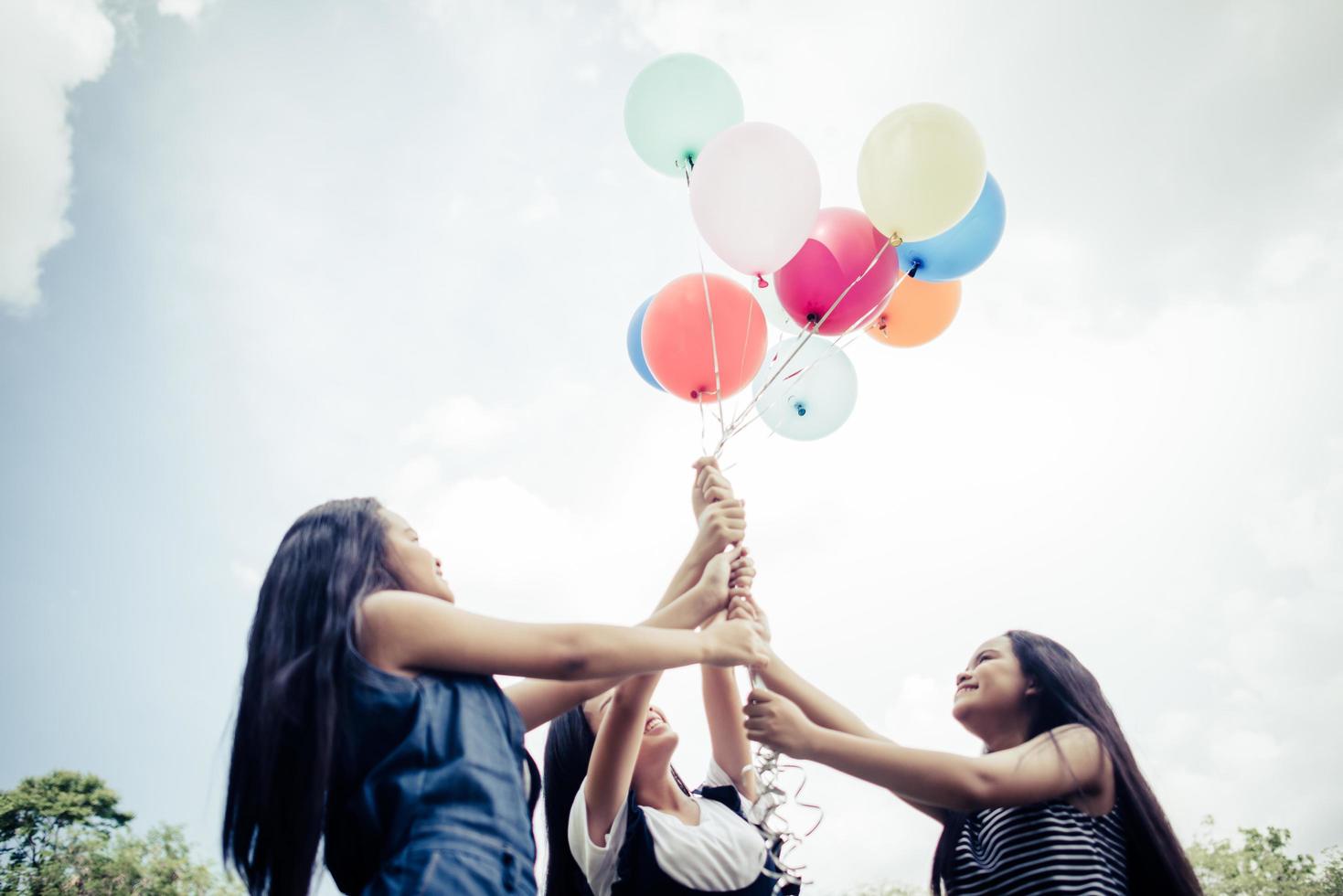 Groupe de copines heureux tenant des ballons multicolores dans un parc photo