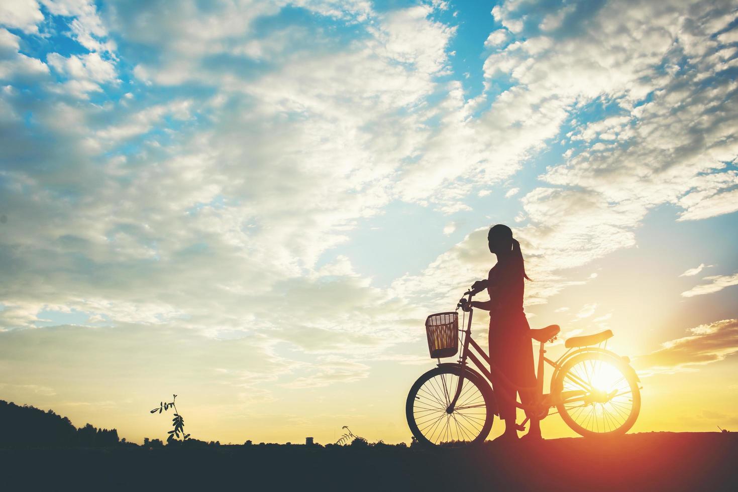 silhouette d'une femme avec un vélo et beau ciel photo