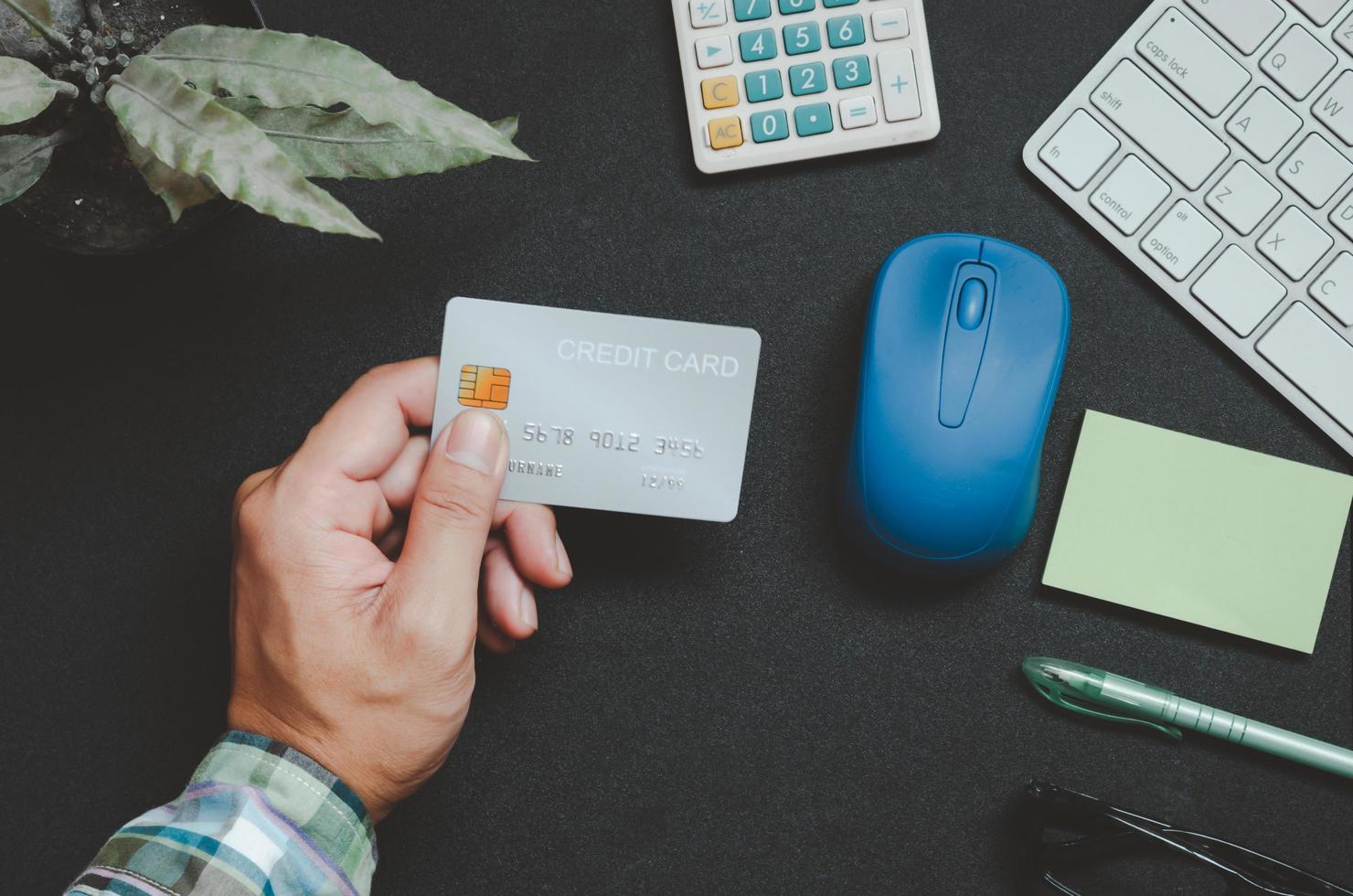 vue de dessus de quelqu'un tenant une carte de crédit sur un bureau photo