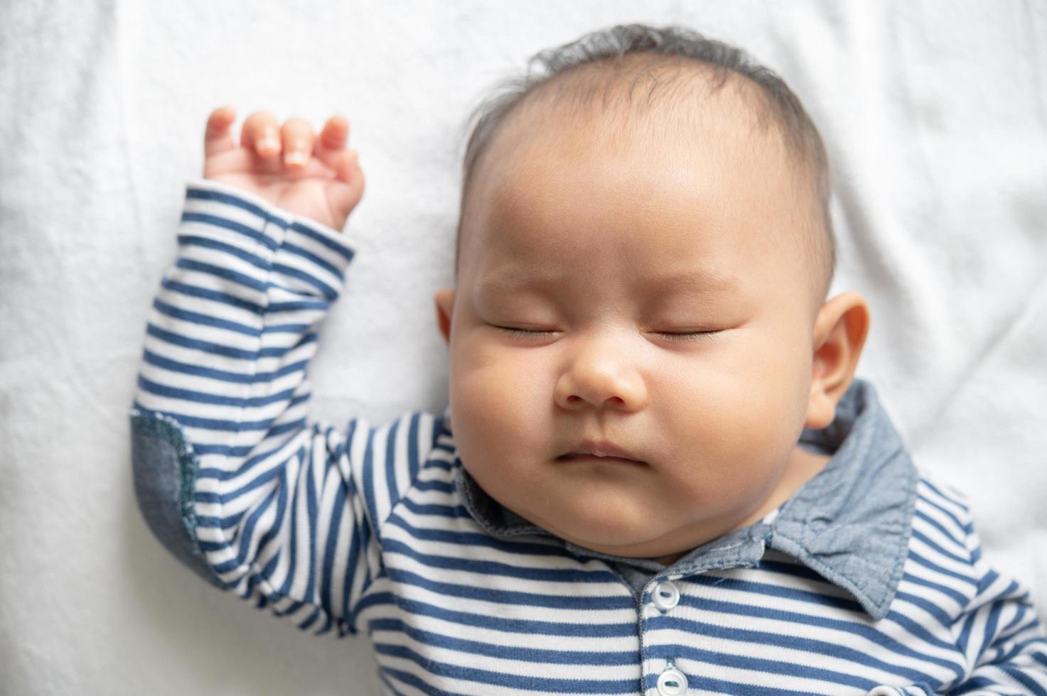 un petit garçon dans une chemise rayée dormant dans son lit photo