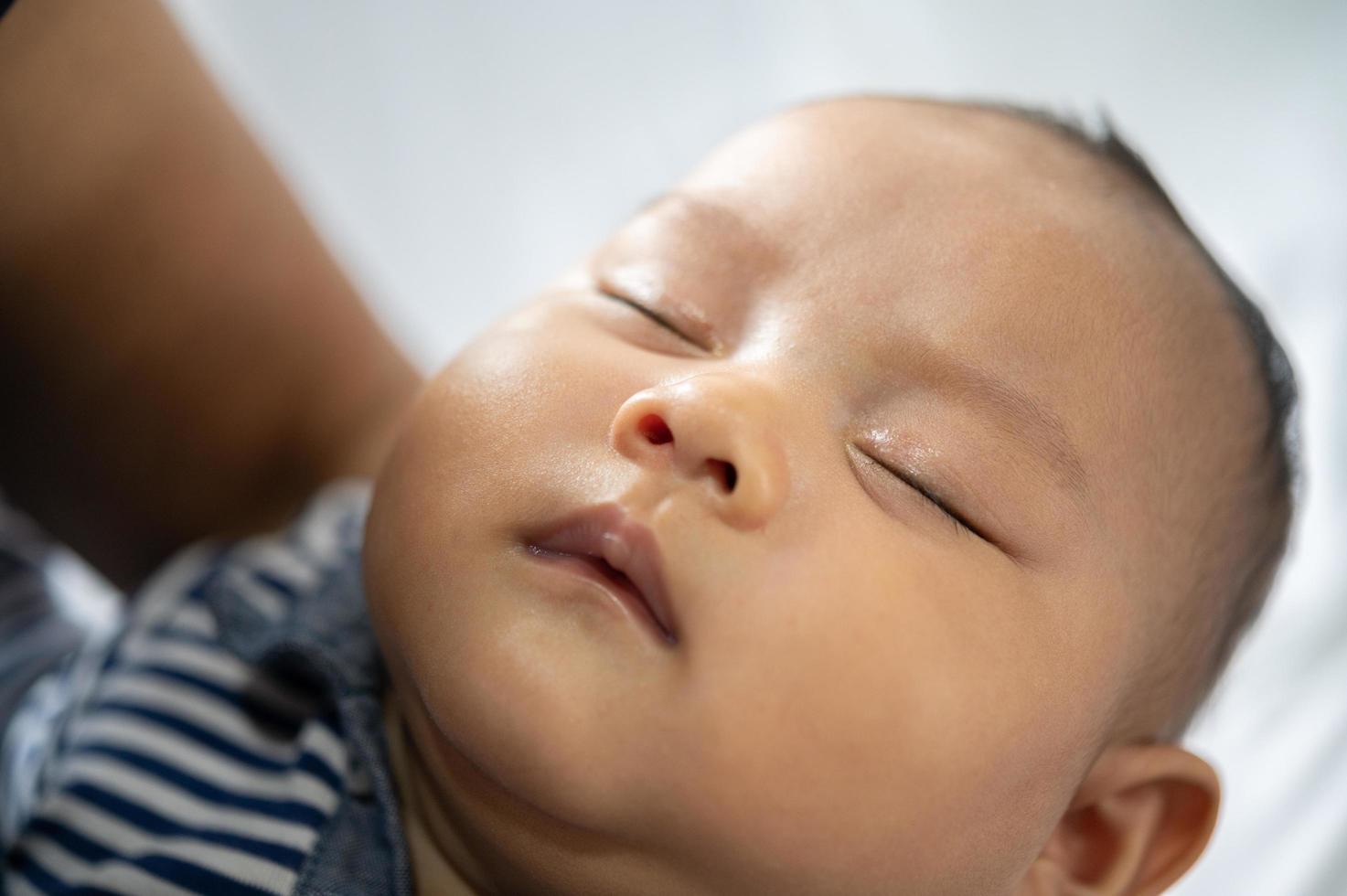 un petit garçon dans une chemise rayée dormant dans son lit photo