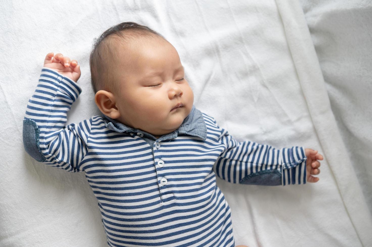 un petit garçon dans une chemise rayée dormant dans son lit photo