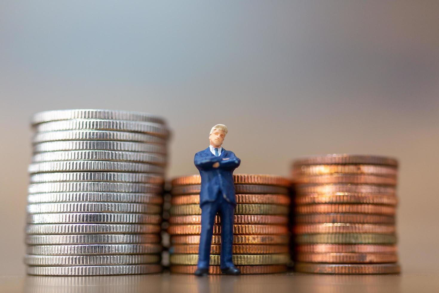 Petits hommes d'affaires miniatures debout avec pile de pièces photo