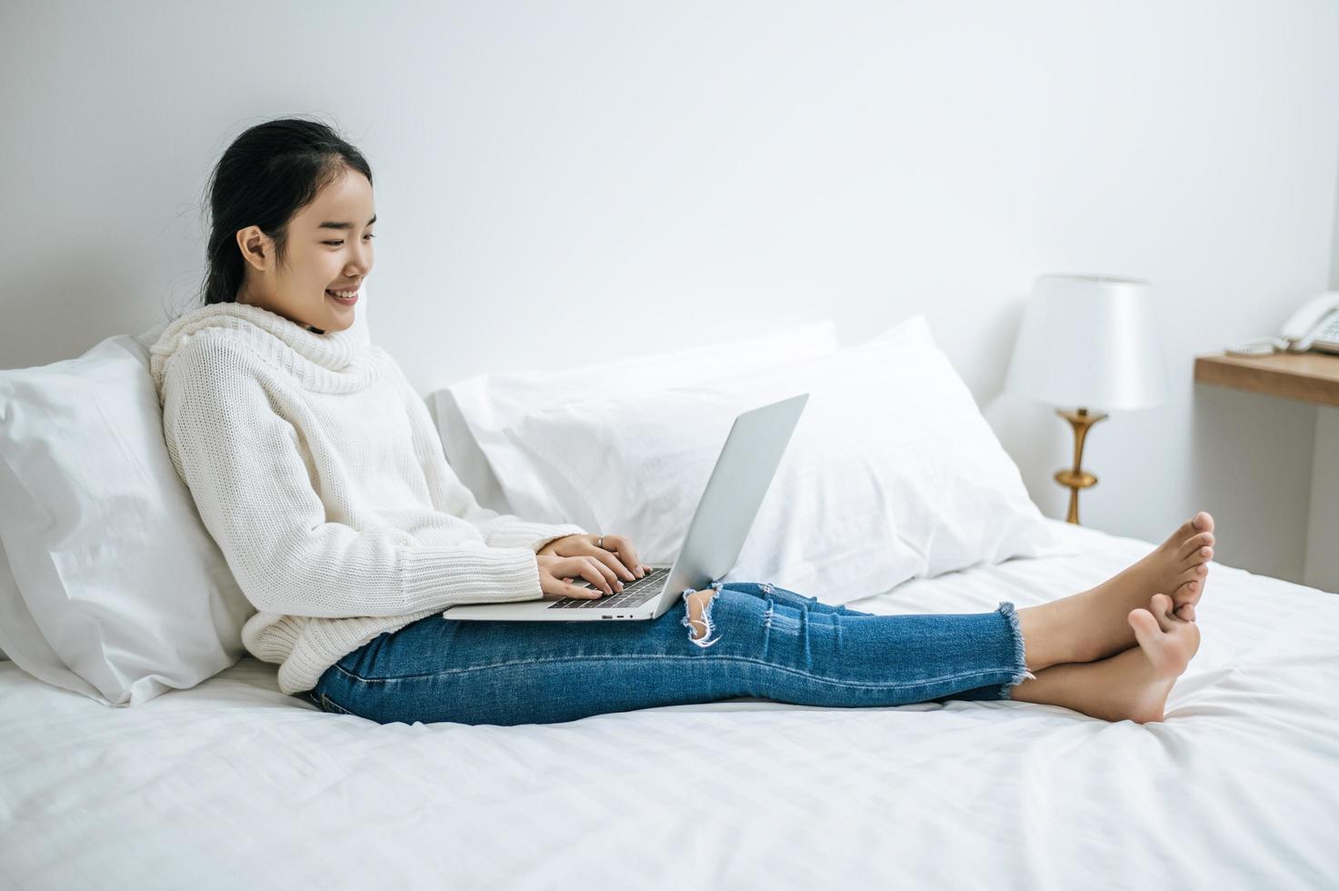 jeune femme portant une chemise blanche jouant sur son ordinateur portable photo