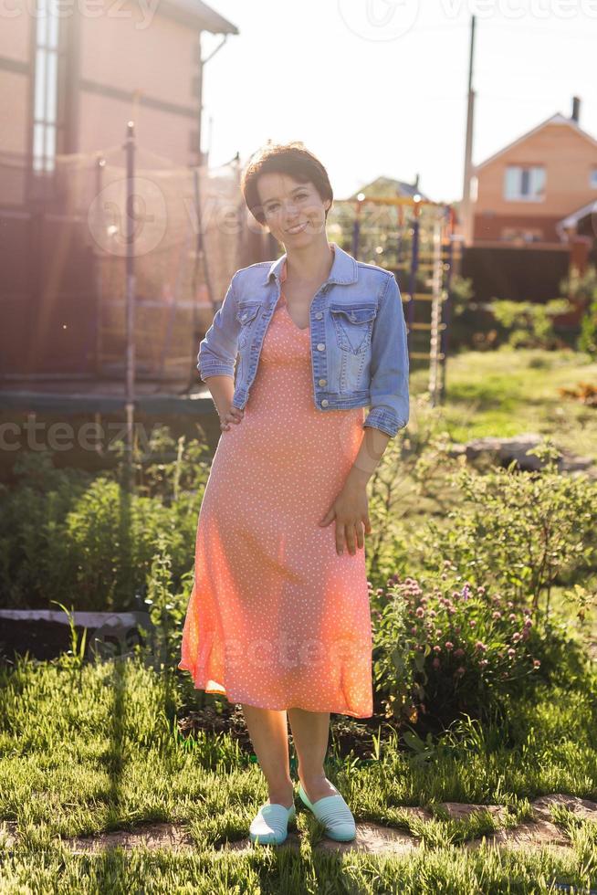 joyeuse jeune femme vêtue d'une robe élégante dans le patio. heureuse fille souriante faisant s'amuser en plein air. heureuse belle femme profitant de l'été photo