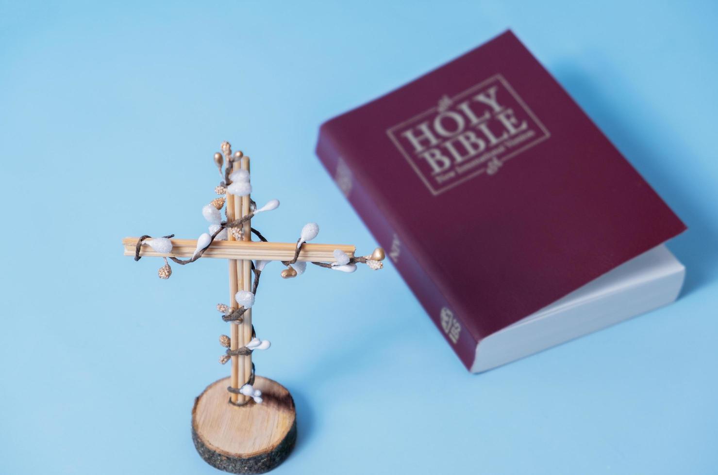 croix décorée de fleurs avec la sainte bible sur fond bleu. concept minimaliste de vacances de pâques photo