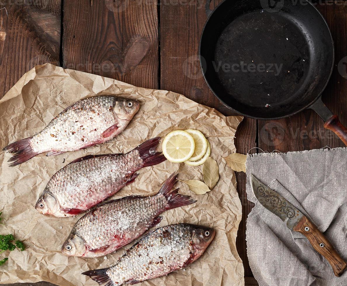 le poisson crucian frais saupoudré d'épices se trouve sur du papier froissé marron photo