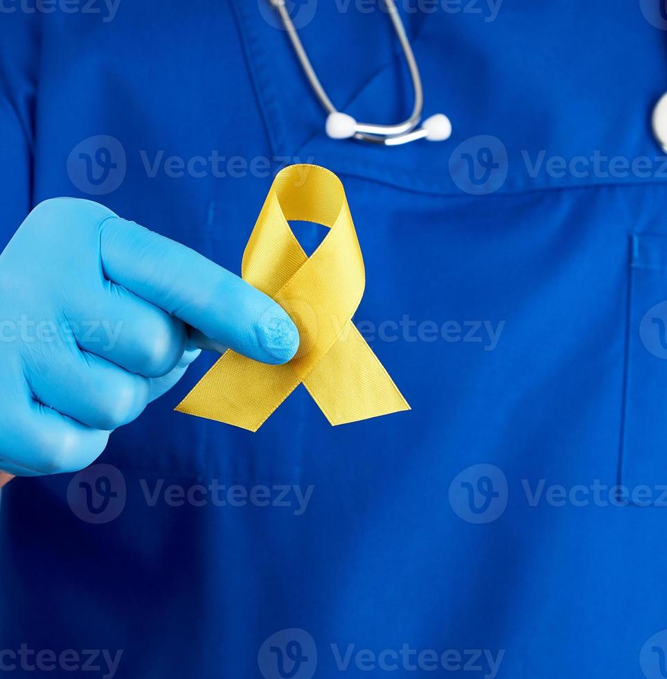 médecin en uniforme bleu et gants stériles en latex tient un ruban jaune dans sa main photo