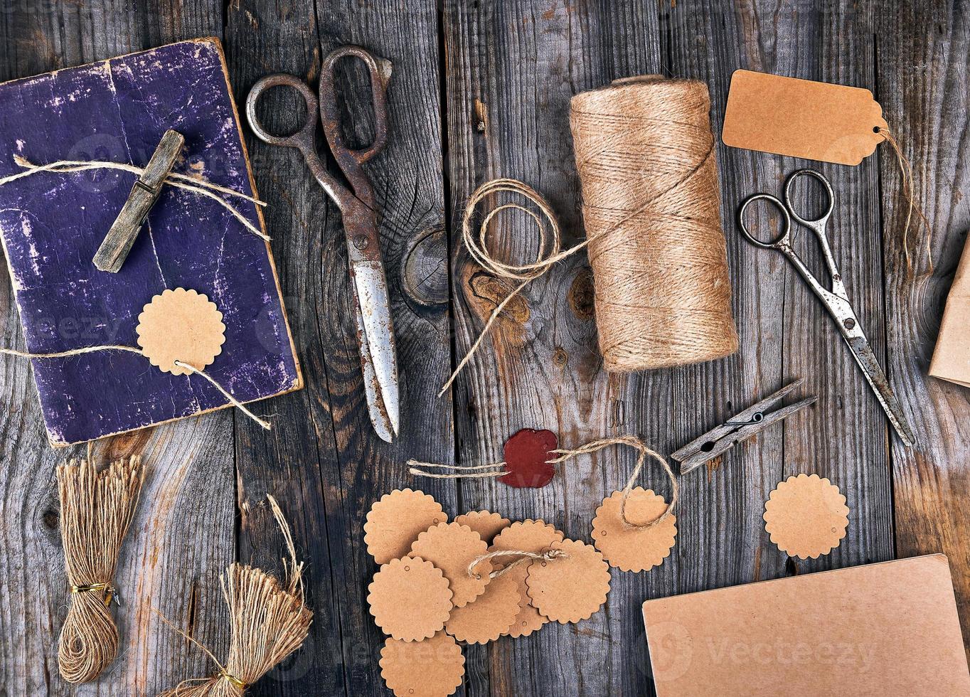 bobine de corde marron, étiquettes en papier et vieux ciseaux sur fond de bois gris photo